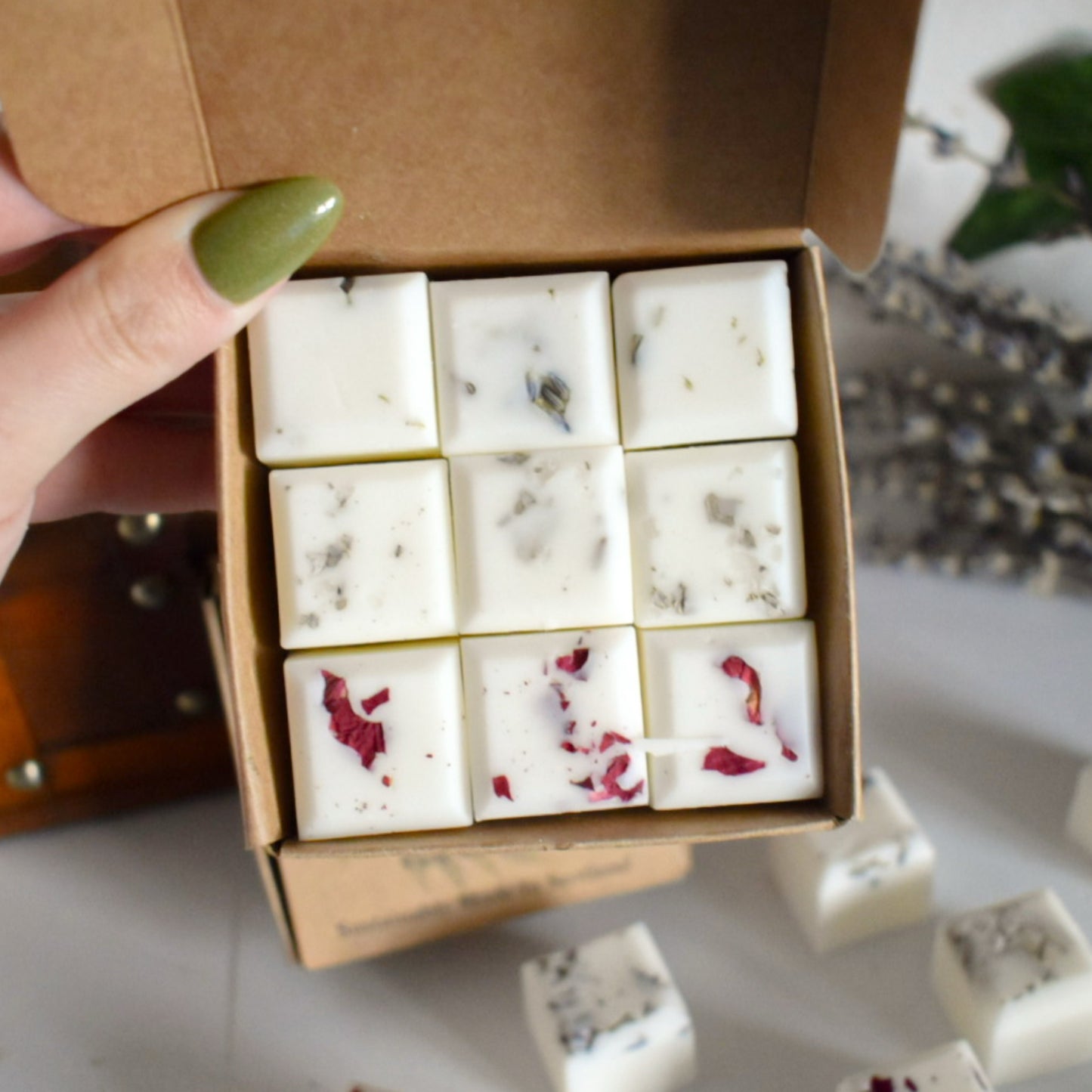 Box of white wax melts with floral designs held by a hand.