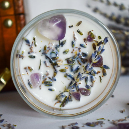 Candle with lavender flowers and a purple crystal on top, surrounded by more lavender flowers.