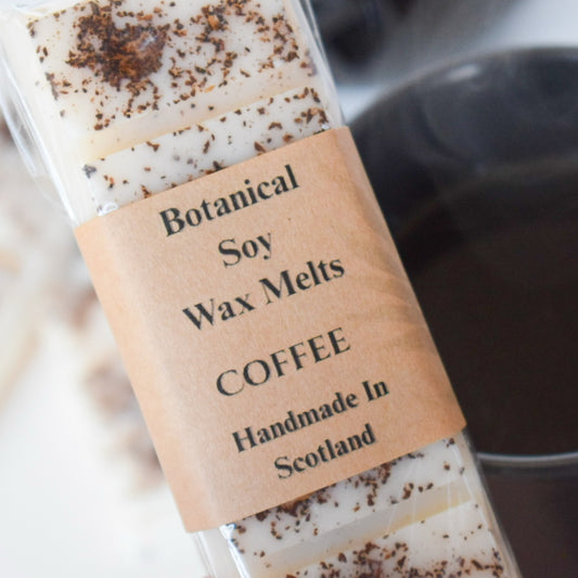 Botanical soy wax melts labeled 'Coffee' handmade in Scotland with a blurred coffee cup in the background.