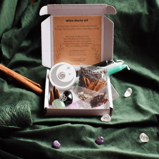 Witch starter kit with spell book, crystals, and other items on a green fabric background