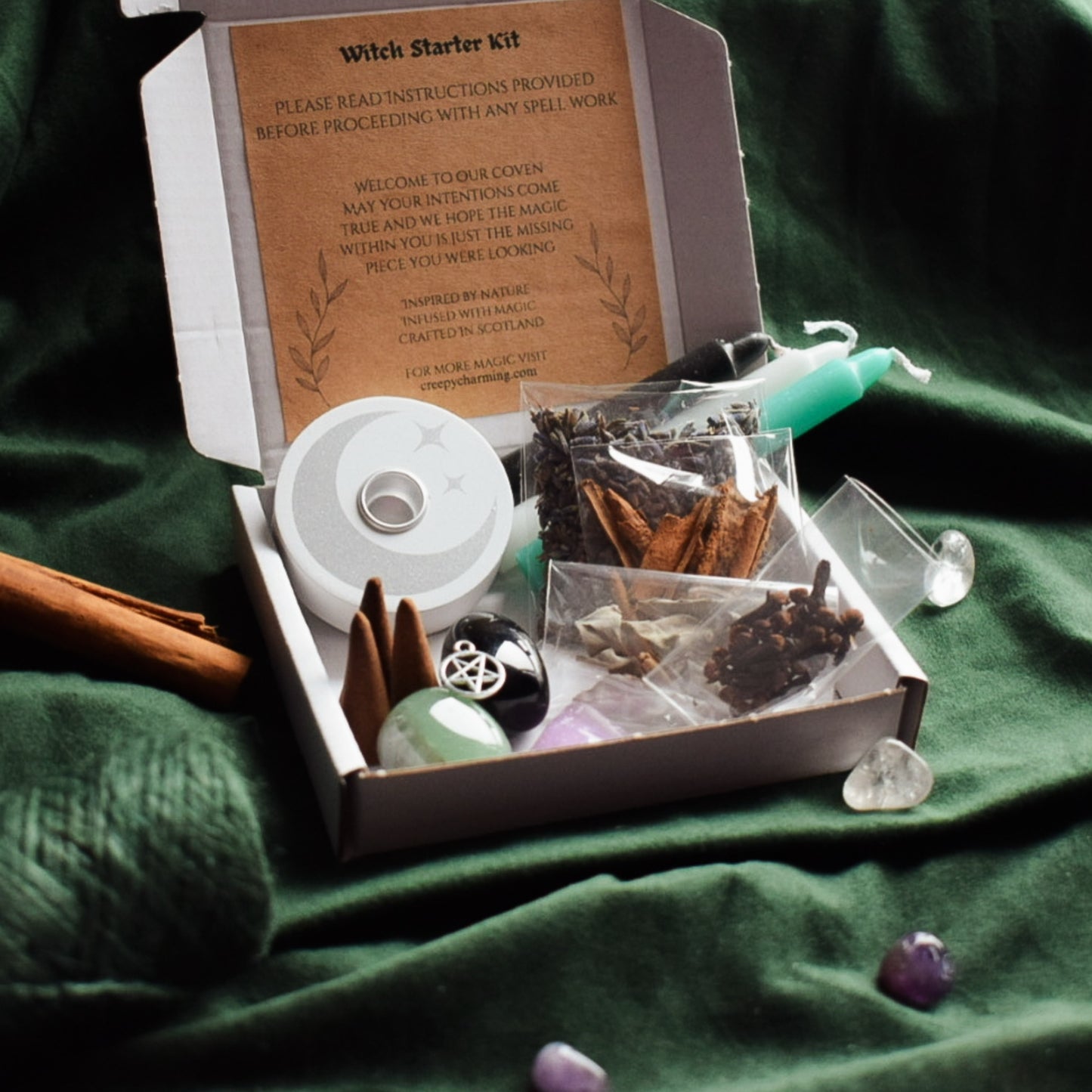 Witch starter kit with herbs, candle, and crystals on a green fabric background